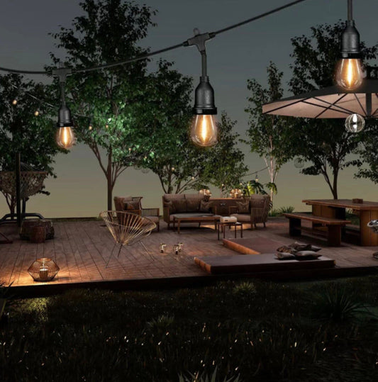 Outdoor patio at night with warm white FEIT LED string lights hanging above seating area, creating a cosy and ambient garden atmosphere