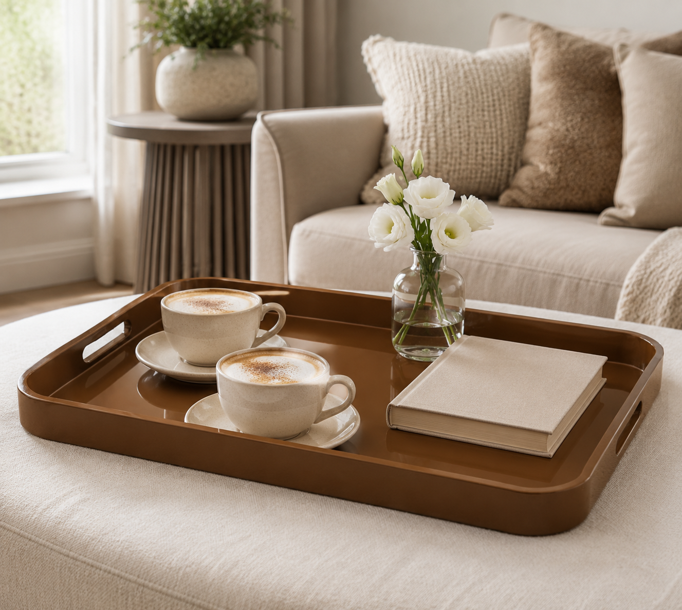 AM.PM Barniz large khaki lacquered serving tray styled with two coffee cups, flowers and a book in a neutral living room.
