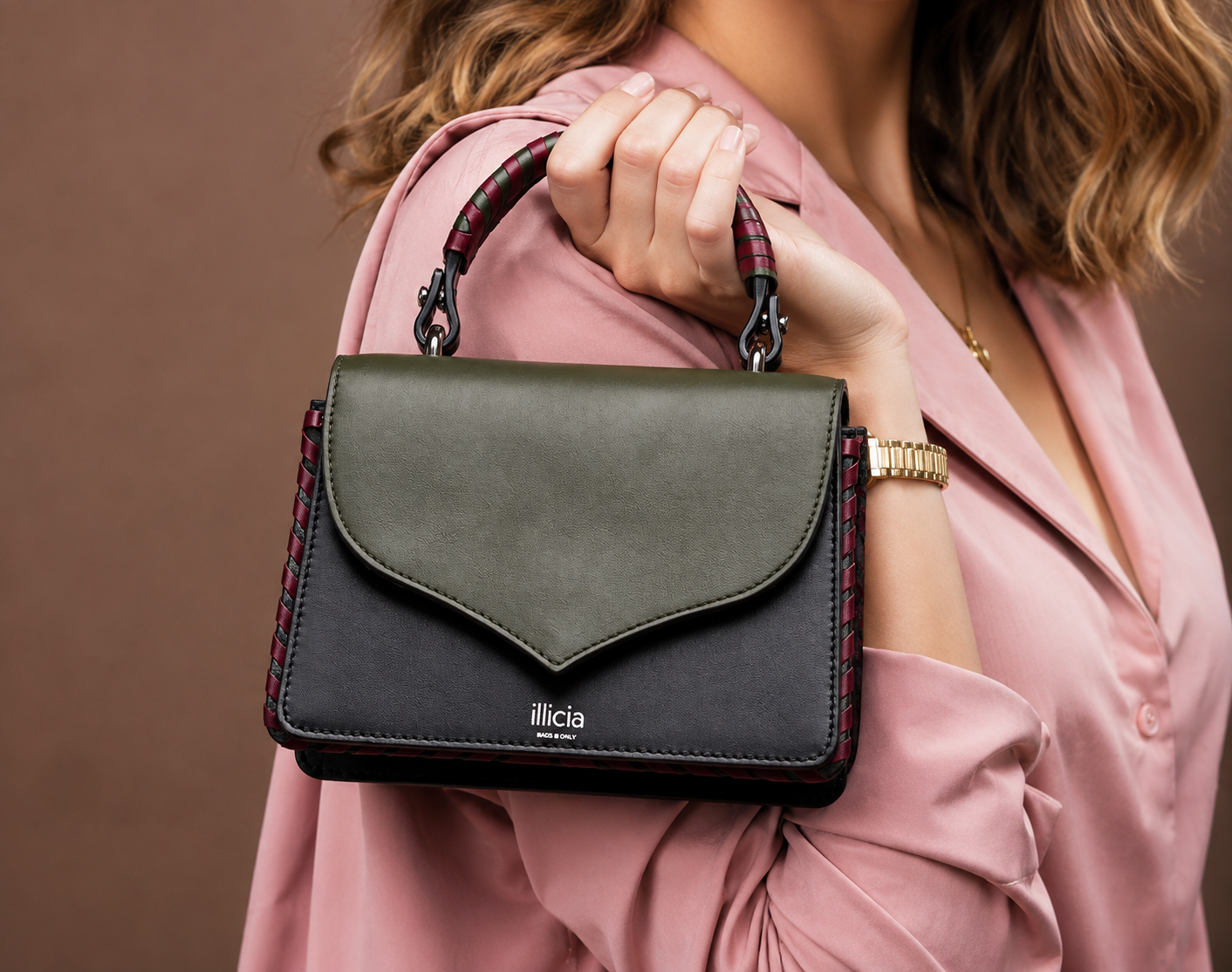 Woman carrying ILLICIA London Celina 2.0 Kale Green and Black leather top handle handbag with a pink outfit