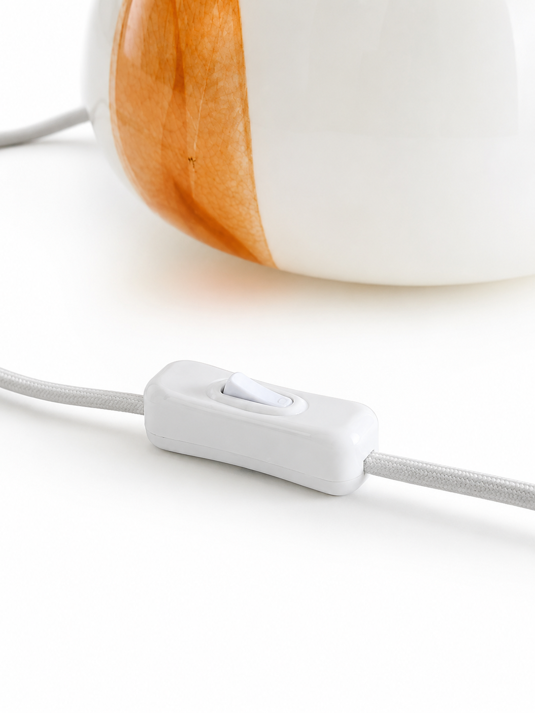 Close-up of The Very Collection spotted glass table lamp featuring the inline on and off cord switch with white braided cable.