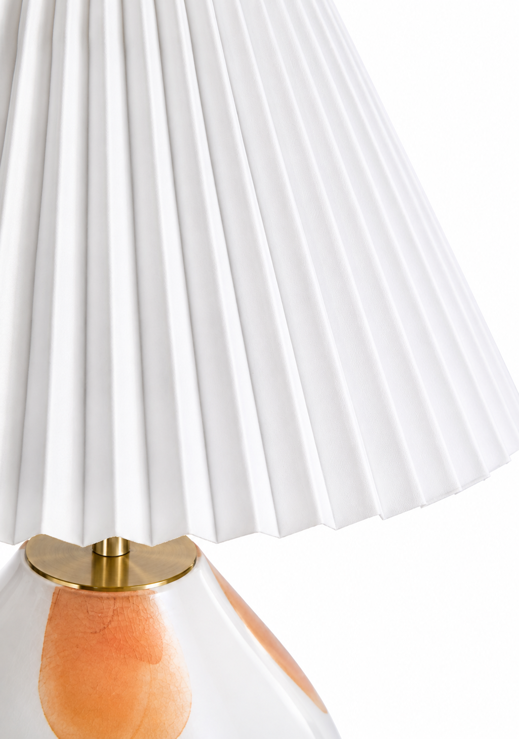 Close-up of The Very Collection table lamp featuring a white pleated fabric shade, brushed brass stem and decorative spotted glass base.
